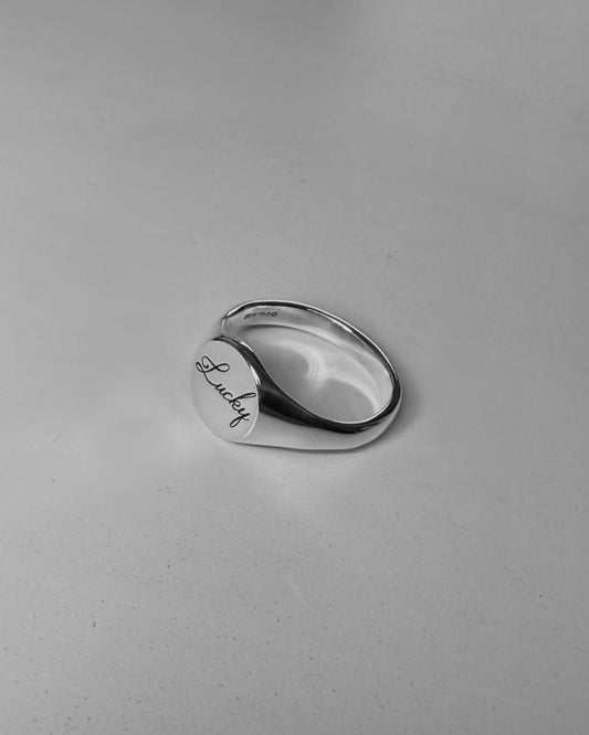 Round silver signet ring with ‘lucky’ engraved on it. Comes on its own. Other rings available on the website